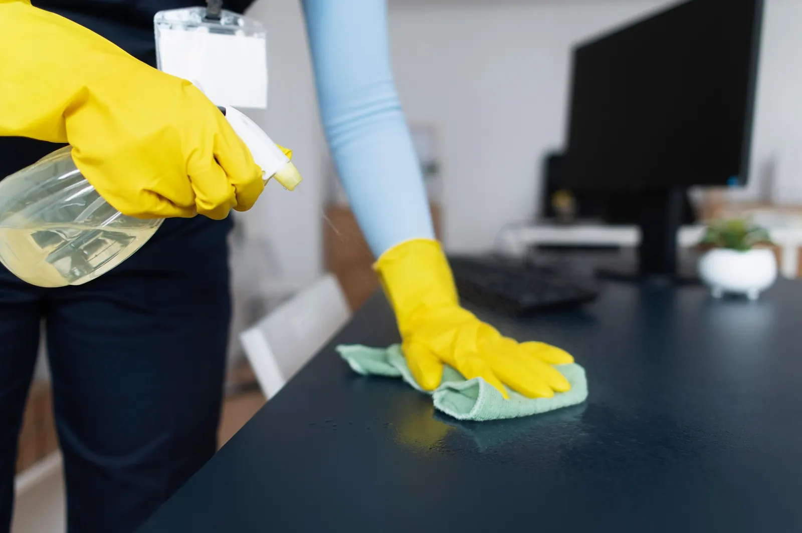 Persona con guantes limpiando y desinfectando un escritorio de oficina